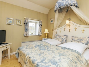 A bedroom with a bed, a bedside table, a lamp, a window with curtains, and framed pictures on the wall. - 4 Person Holiday Home in Faaborg (Faaborg)