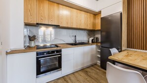 A modern kitchen with wooden cabinets, a stainless steel refrigerator, a built-in oven, and a wooden dining table. - Adriatic Escape Apartment Steps From the Beach (Shengjin)