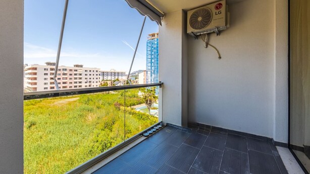 A balcony with a view of buildings and greenery, an LG air conditioner, and a tiled floor. - Adriatic Escape Apartment Steps From the Beach (Shengjin)