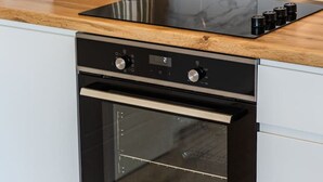 A kitchen with a built-in oven and stovetop, a marble backsplash, and a wooden countertop. - Adriatic Escape Apartment Steps From the Beach (Shengjin)