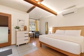 Ein Hotelzimmer mit einem großen Bett, einer Holzbalkendecke, einem Schreibtisch, einem Stuhl und einem kleinen Tisch mit einer Pflanze.