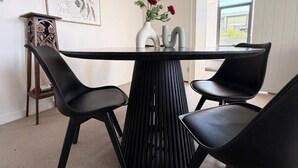 Un comedor moderno con una mesa y sillas negras, un florero con flores e ilustración botánica enmarcada en la pared.
