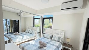 Un dormitorio con una cama grande, una cama más pequeña, un escritorio y un espejo.