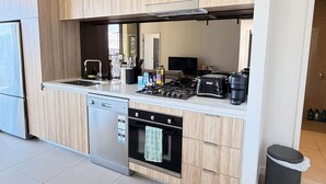 Una cocina moderna con armarios de madera, lavavajillas, horno, estufa a gas y pileta.