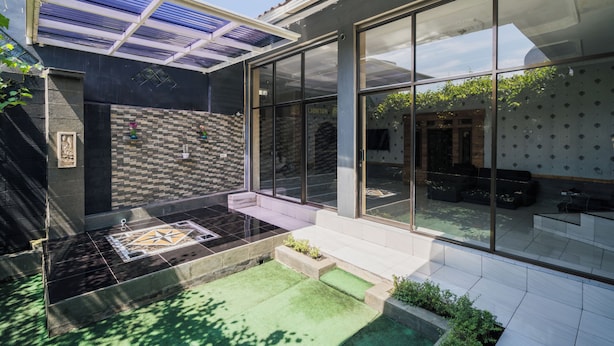 Una casa moderna con un invernadero de vidrio, un patio empedrado y un pequeño jardín.