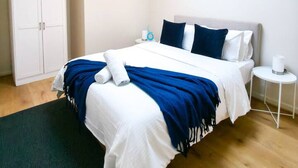 Ein modernes Hotelzimmer mit einem großen Bett, einer Deckenleuchte, einem Kleiderschrank und einem kleinen Nachttisch.