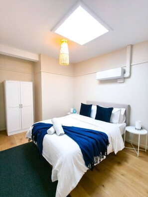 Une chambre d’hôtel moderne avec un grand lit, un luminaire au plafond, une armoire et une petite table de chevet.