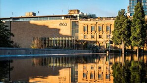 Ein Gebäude mit einem spiegelnden Wasserspiegel davor, das moderne und klassische Architektur vereint.