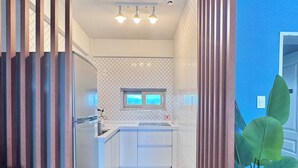 A modern kitchen with a central island, a wooden partition, and a potted plant. - Spring Breeze Stay (Jeju City)