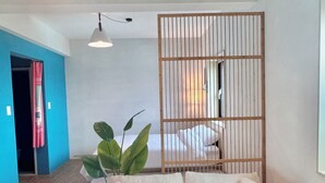 A modern living room with a sectional sofa, a wooden partition, and a ceiling light fixture. - Spring Breeze Stay (Jeju City)