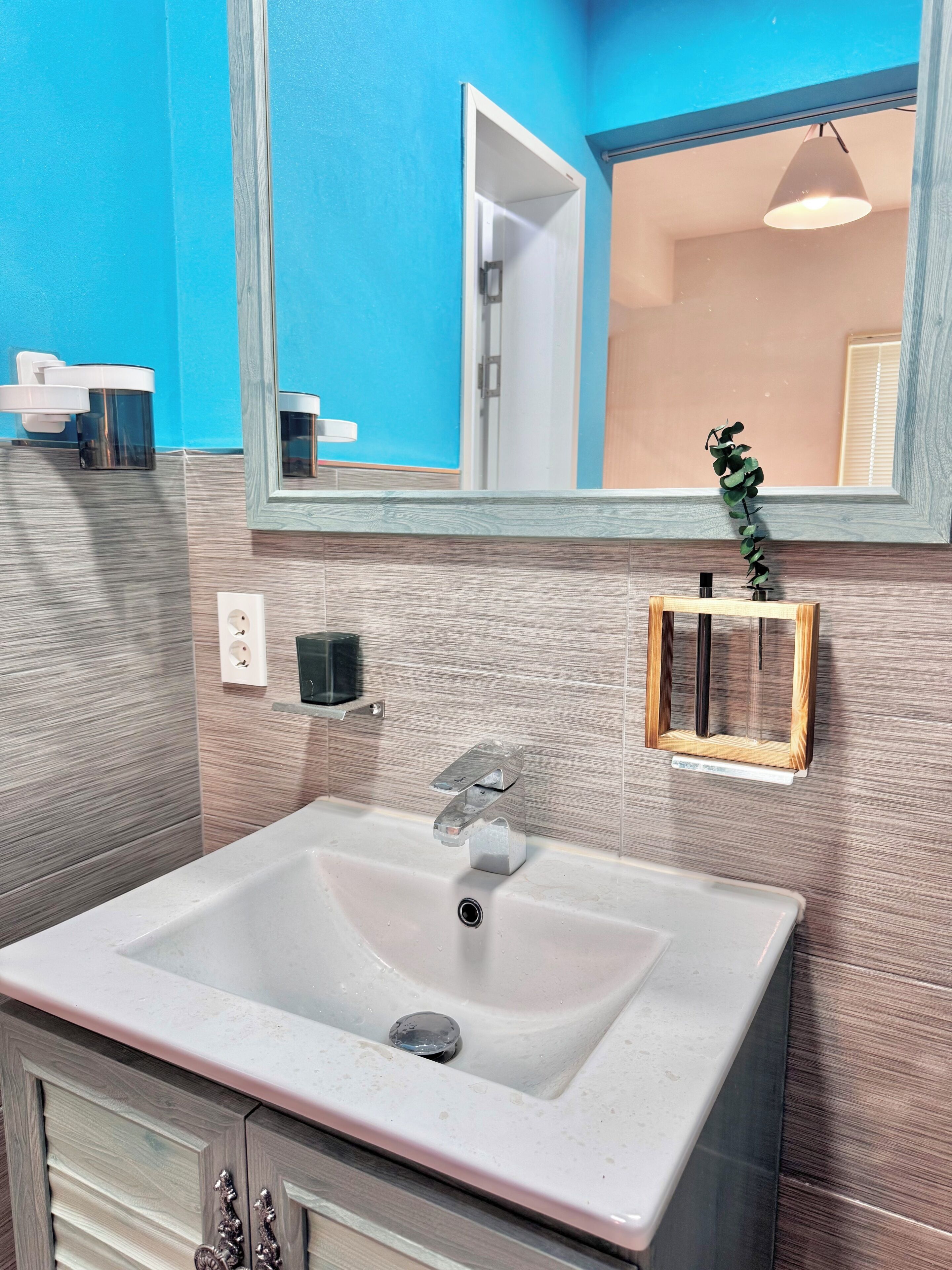 A bathroom with a white sink, a mirror, a towel rack, and a potted plant.