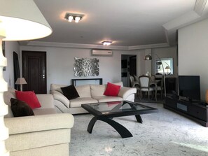 Un salon comprenant un canapé, une table basse, un téléviseur et un coin repas.