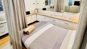 Ein modernes Schlafzimmer mit einem großen Bett, einem integrierten Fernseher und einem großen Spiegel.