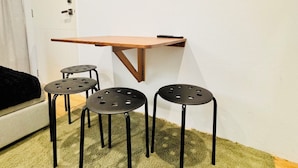 Ein Zimmer mit einem kleinen Tisch, drei Hocker, einer Tür und einem Sofa.
