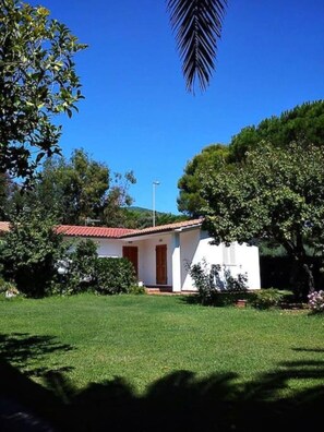 A small white building with a red roof, surrounded by greenery and trees. - Aria di Mare - Cottage (Capoliveri)