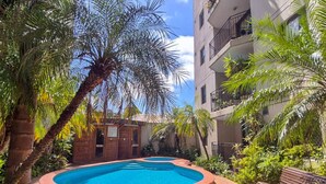A swimming pool surrounded by palm trees and a building with balconies. - Central Loft on Broadway + Parking/Pool (Glebe)
