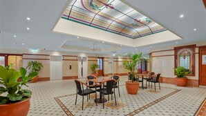 A spacious hotel lobby with a high ceiling, patterned floor, and multiple seating areas. - Central Loft on Broadway + Parking/Pool (Glebe)