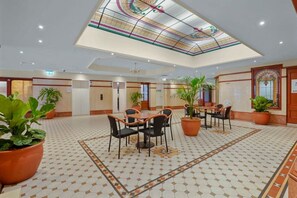 A spacious hotel lobby with a high ceiling, patterned floor, and multiple seating areas. - Central Loft on Broadway + Parking/Pool (Glebe)