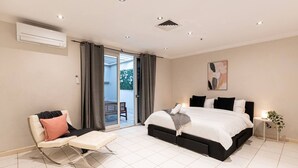 A bedroom with a bed, a chair, a small table, and a window. - Luxury Penthouse with Natural Light (Glebe)