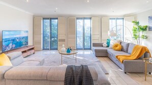 A modern living room with a sofa, a coffee table, and a TV. - Luxury Penthouse with Natural Light (Glebe)