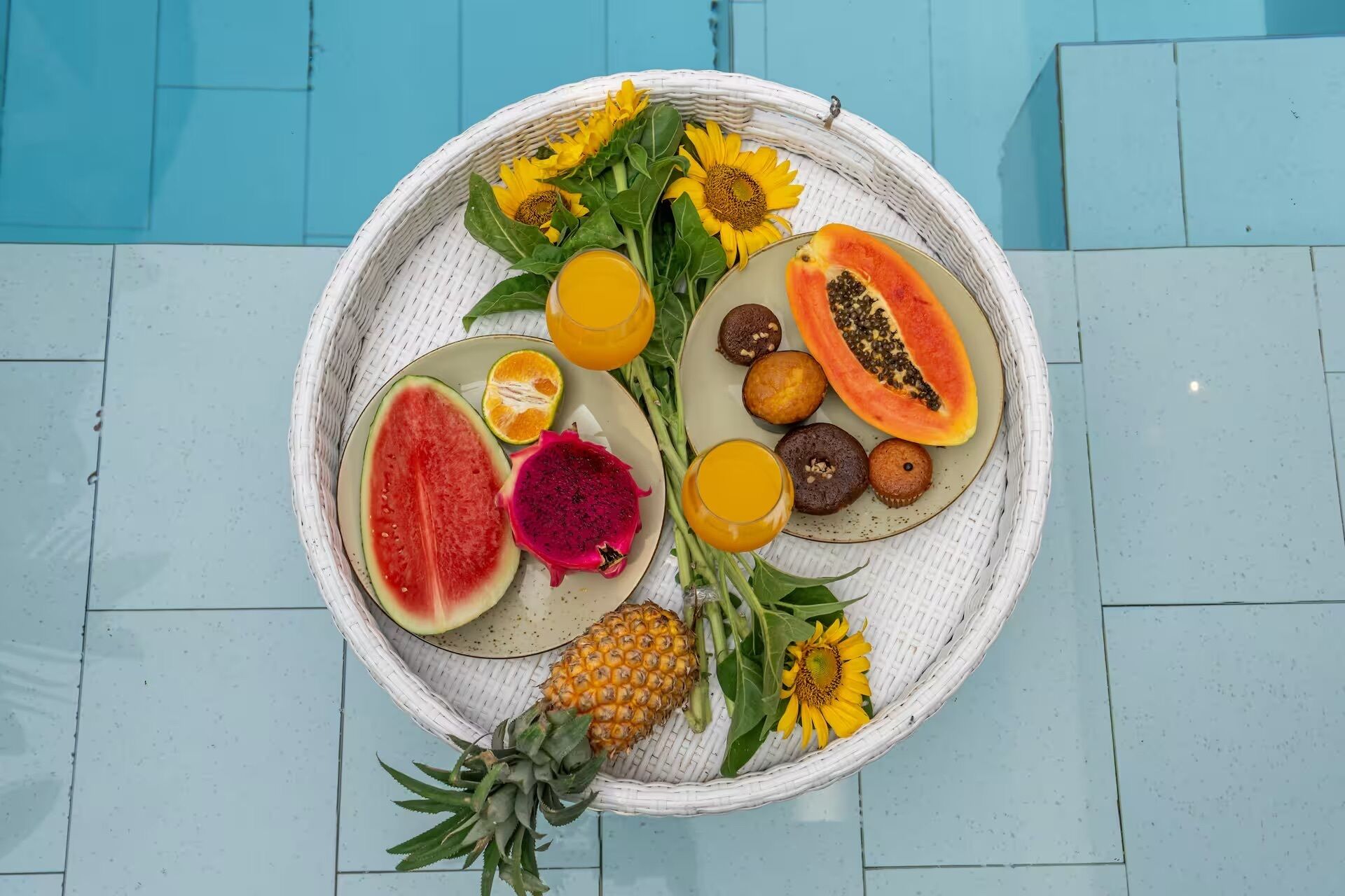 Ein Korbtablett mit Obstscheiben, einer Ananas und einer Sonnenblume.