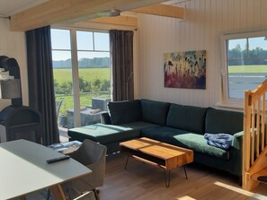 Ein modernes Wohnzimmer mit einem grünen Sofa, einem Holztisch, einem Fernseher und einem Bild an der Wand.