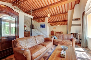 Ein geräumiges Wohnzimmer mit Ledersofas, einem Holztisch und einer Treppe, die zu einer oberen Ebene führt.