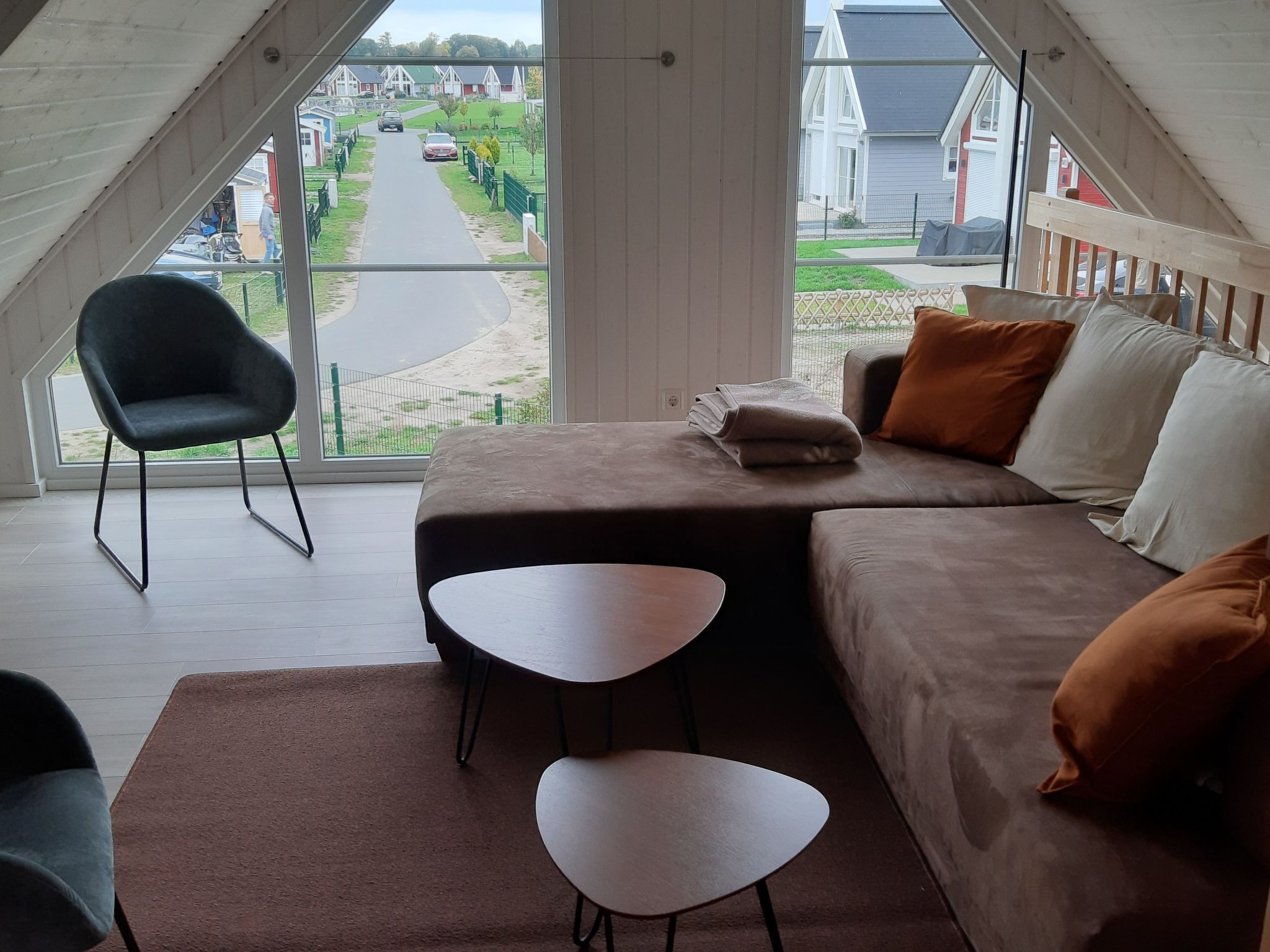 A modern loft bedroom with a large window, a sofa, a small table, and a chair.