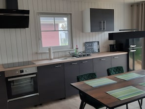 Eine kompakte Küche mit integriertem Ofen, einem Fenster und einem Essbereich mit Tisch und Stühlen.