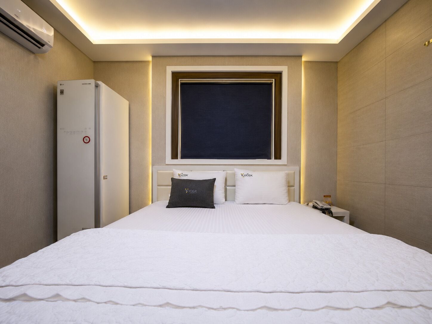 A hotel room with a bed, a nightstand, a phone, and a window with a view.