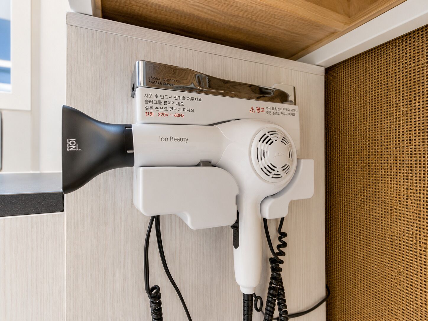 A hair dryer mounted on a wall with a wooden panel above it.