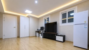 Una cocina moderna con un televisor de pantalla plana, un refrigerador y piso de madera.