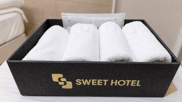 Una caja negra con el texto 'SWEET HOTEL' y un logo, que contiene toallas blancas dobladas con cuidado.
