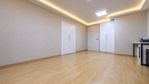 Una habitación amplia con piso de madera, paredes blancas e iluminación empotrada en el techo.