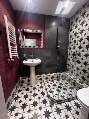A bathroom with a star-patterned floor, a pedestal sink, a mirror with a star border, and a shower area. - Hotel Kalanga (T'bilisi)