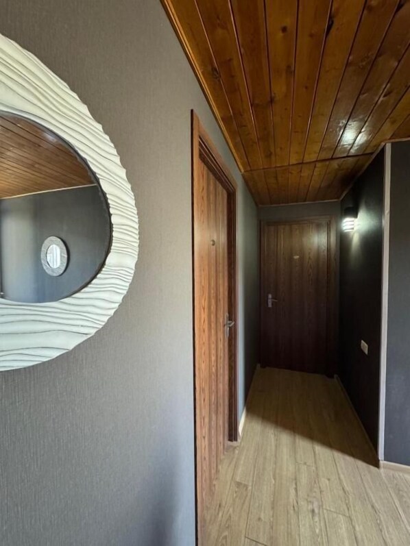 Un pasillo con techo de madera, un adorno circular en la pared y una puerta.
