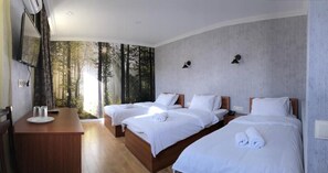 A hotel room with two beds, a wooden desk, and a large window with a forest view. - Hotel Kalanga (T'bilisi)