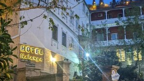 Um hotel com uma placa indicando 'HOTEL RALANGA', fachada de tijolos e uma varanda com grades.