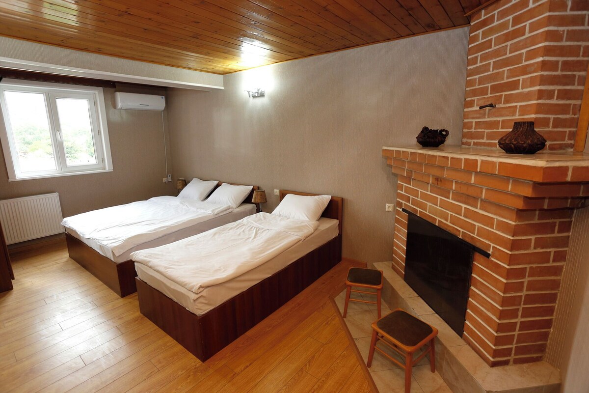 A room with two beds, a fireplace, and a window.