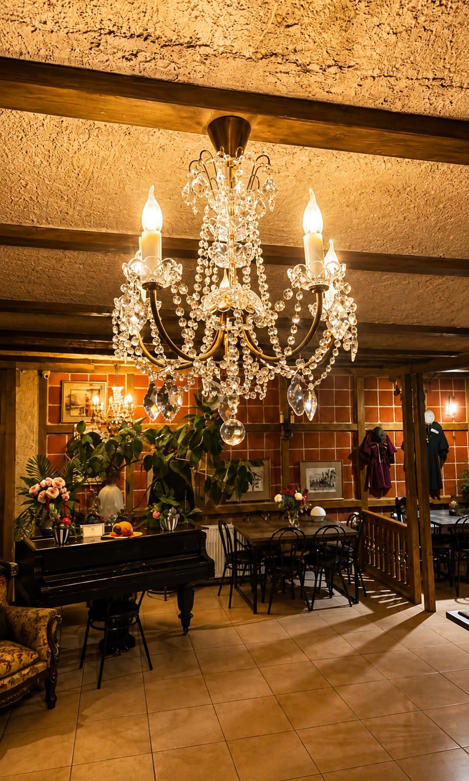 Un candelabro con múltiples velas, un piano, una mesa de comedor, sillas y una zona de bar con un espejo y cuadros enmarcados.