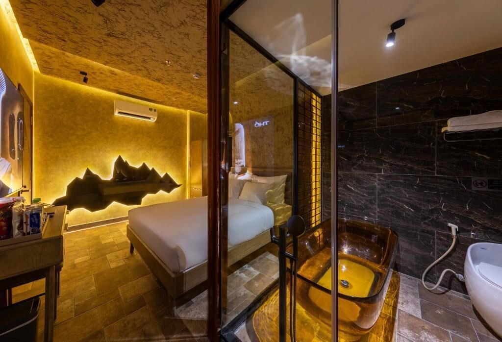 A modern hotel room with a bed, a glass-enclosed bathtub, and a shower.