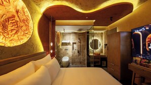 Quarto de hotel com cama, espelho grande, chuveiro e televisão.