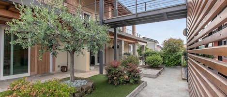 A modern building with a covered walkway, outdoor seating, and landscaped garden areas.