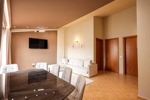 A modern living room with a dining table, sofa, and a flat-screen TV mounted on the wall. - Rooftop Apartments 02 With Balcony Next to Fafa (Golem)