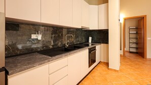 Una cucina con mobili bianchi, un piano di lavoro nero, un lavello e un forno.