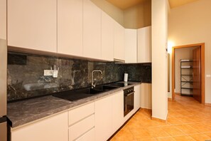 A kitchen with white cabinets, a black countertop, a sink, and an oven. - Rooftop Apartments 02 With Balcony Next to Fafa (Golem)