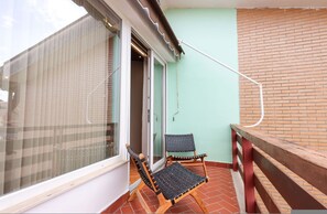 A balcony with two wicker chairs, a glass door, and a brick wall. - Rooftop Apartments 02 With Balcony Next to Fafa (Golem)