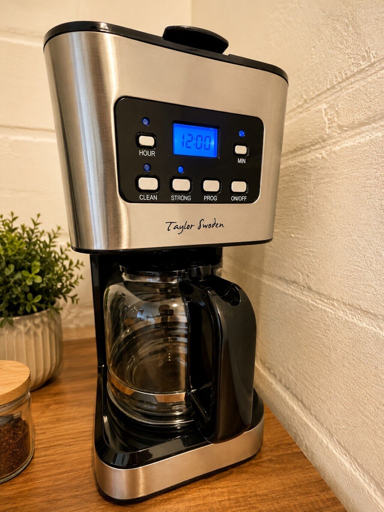 En stål kaffemaskine med digitalt display, mærket 'Taylor Swoden,' på en træoverflade.
