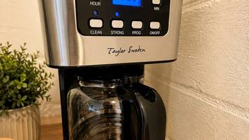 En stål kaffemaskine med digitalt display, mærket 'Taylor Swoden,' på en træoverflade.