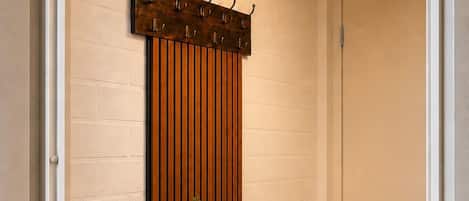 A hallway with a wooden bench, a wall-mounted coat rack, and a hanging light fixture.